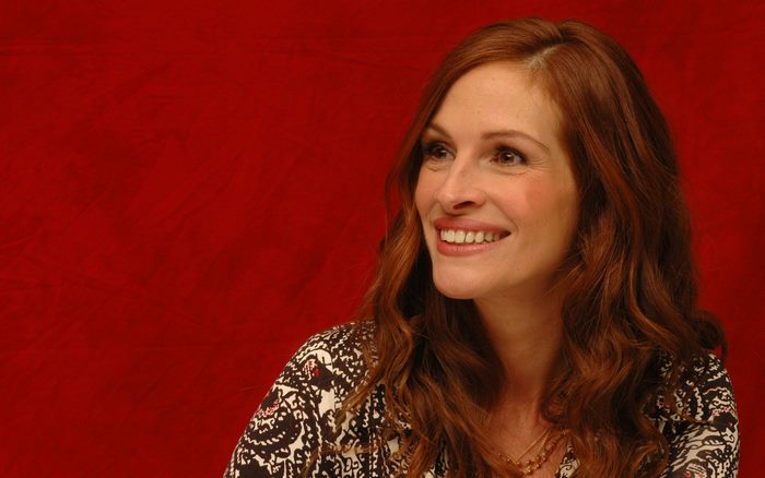 Julia Roberts smiling against a red background