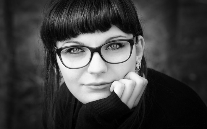 Woman with glasses resting her chin on her hand