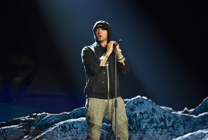 Eminem performing on stage with mountain backdrop