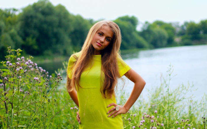 Young woman in yellow dress by a lake