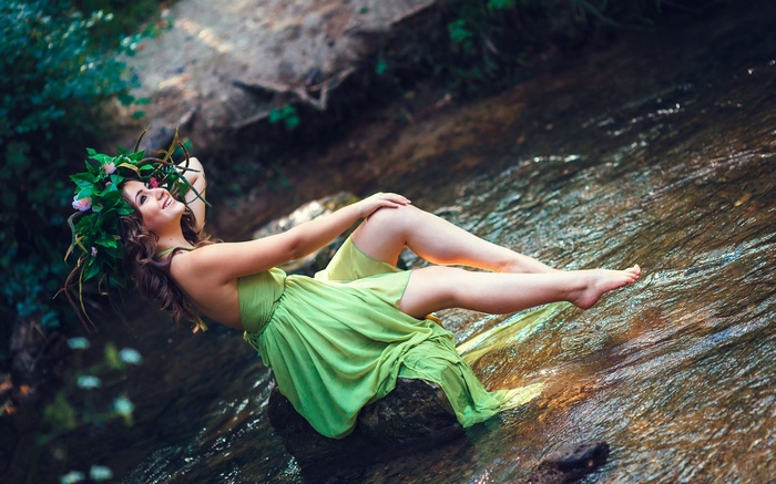 Woman in green dress with flower crown in stream