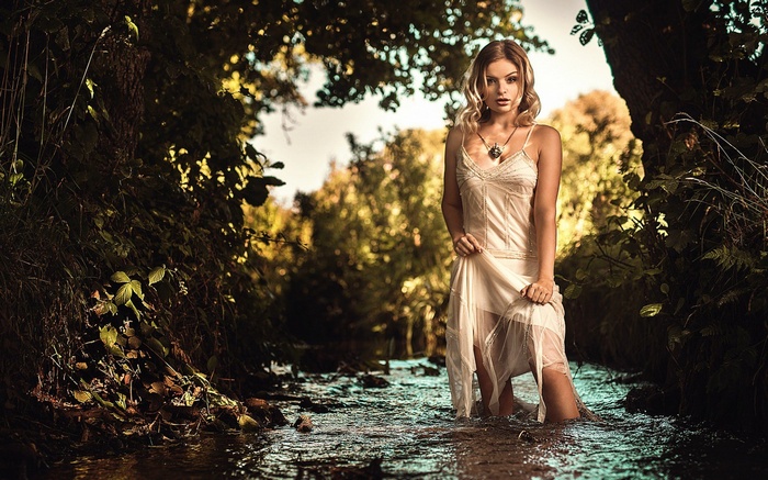 Woman in a white dress standing in a stream