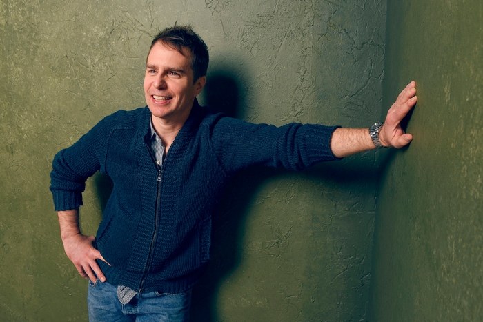 Sam Rockwell leaning against a green wall