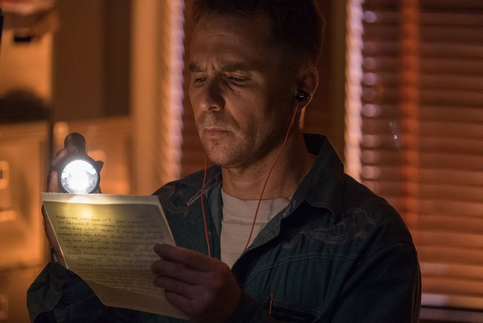 Sam Rockwell reading a letter with a flashlight