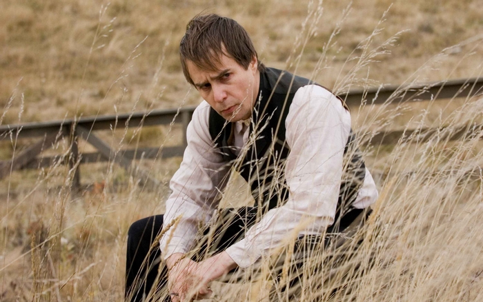 Sam Rockwell sitting in tall grass