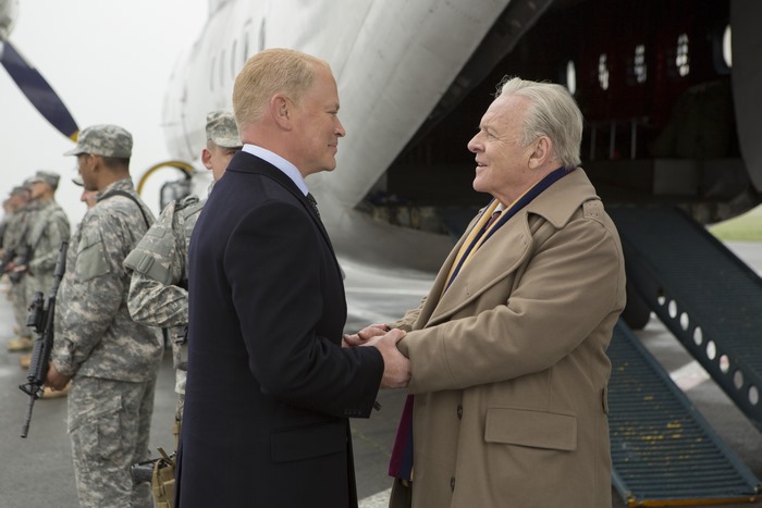 Anthony Hopkins and another man shaking hands near an airplane