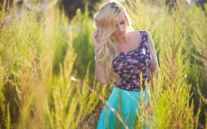 Woman with blonde hair in a floral top and turquoise skirt