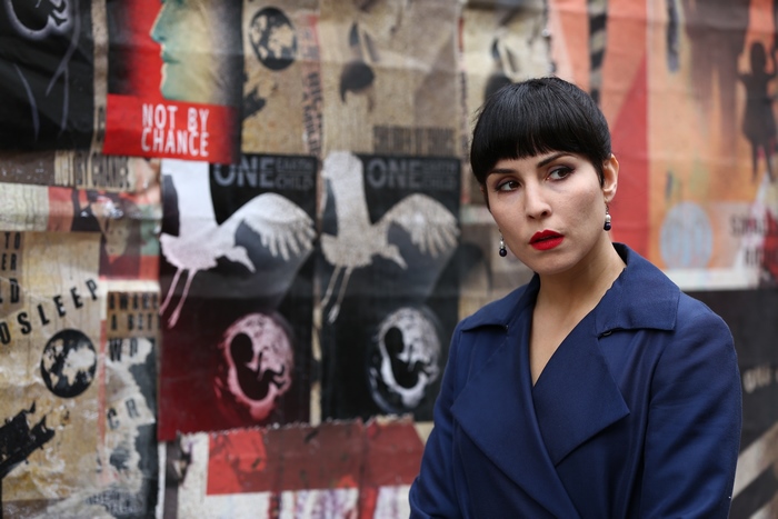 Noomi Rapace in front of a collage of posters