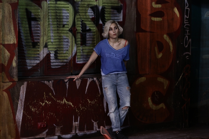 Noomi Rapace leaning against graffiti wall