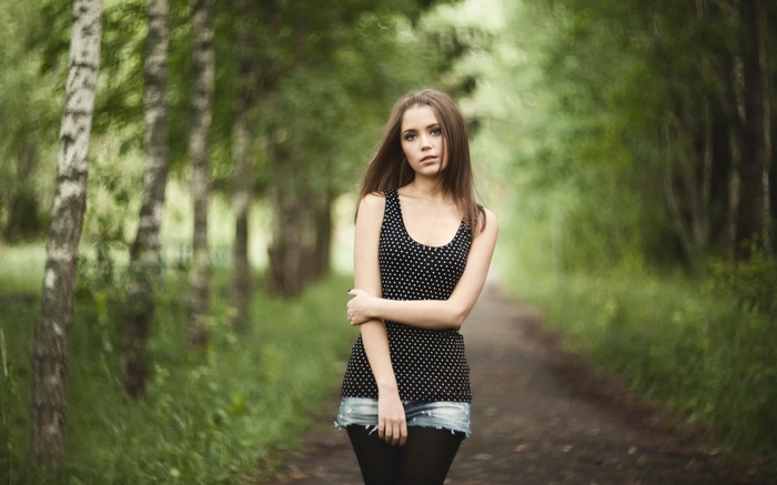 Young woman standing on a path in a forest
