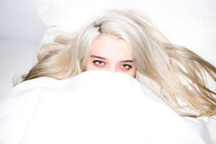 Sky Ferreira peeking from under white sheets