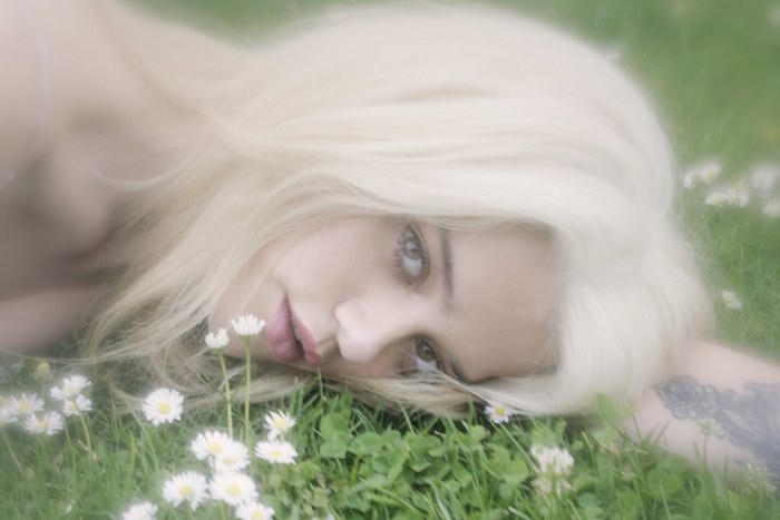 Sky Ferreira lying in grass with daisies