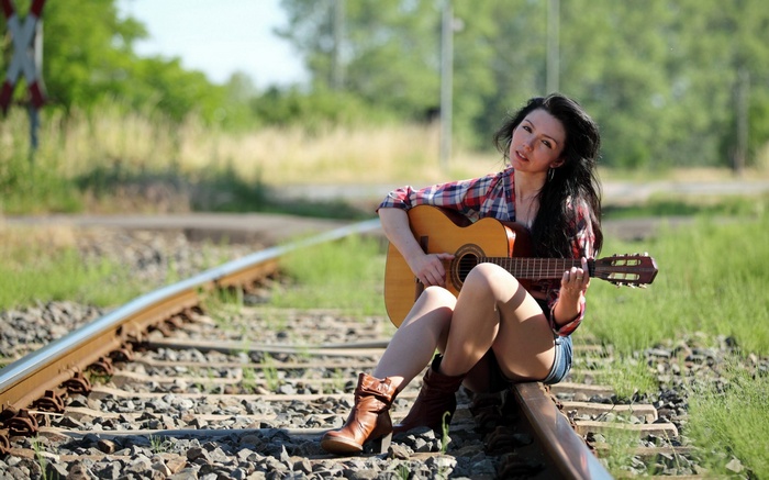 Woman playing guitar on train tracks