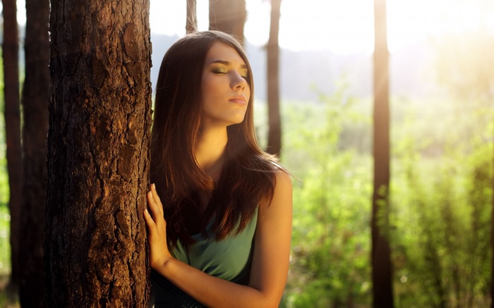 Woman leaning against a tree in a forest