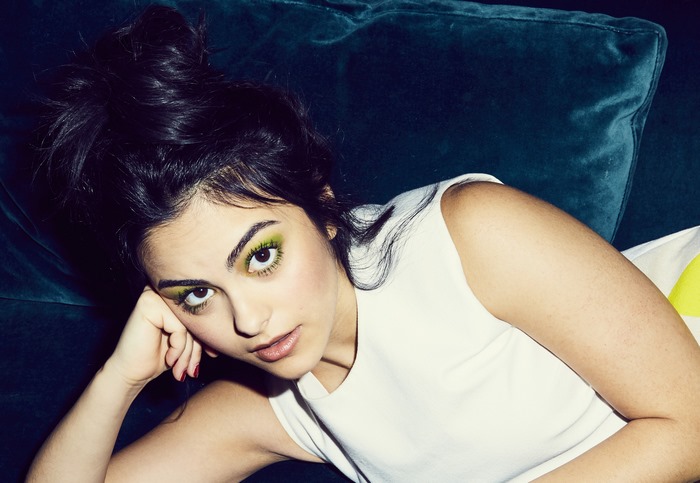 Camila Mendes lying on a teal couch