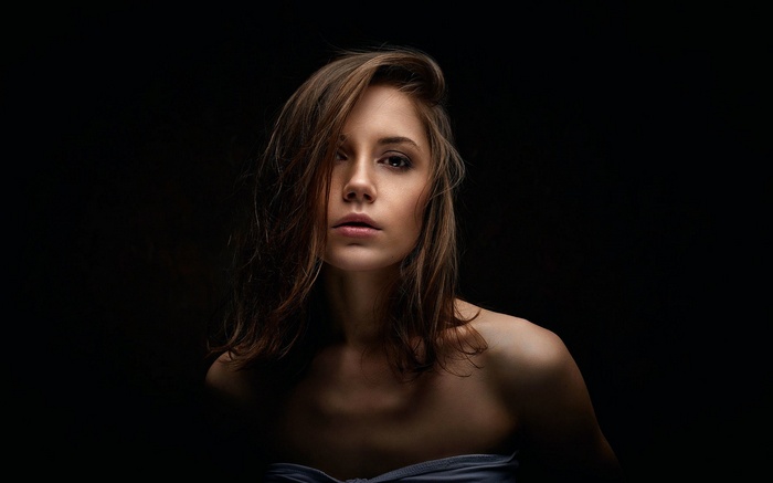 Woman with brown hair against a black background