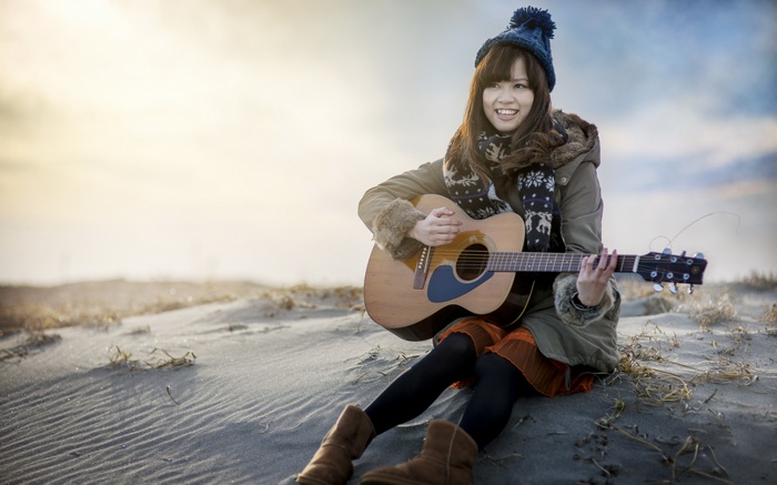 Woman playing guitar on a sandy beach