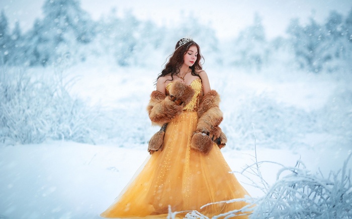 Woman in yellow dress and fur coat in snow