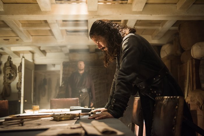 Luke Arnold in a dimly lit room with nautical instruments