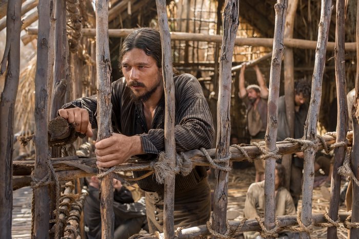 Luke Arnold in a wooden prison