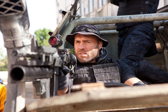 Randy Couture aiming a rifle