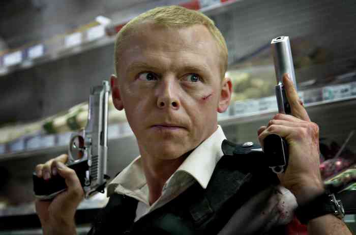 Simon Pegg holding two handguns