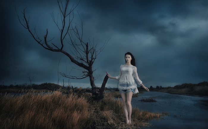 Woman in white dress by a dead tree