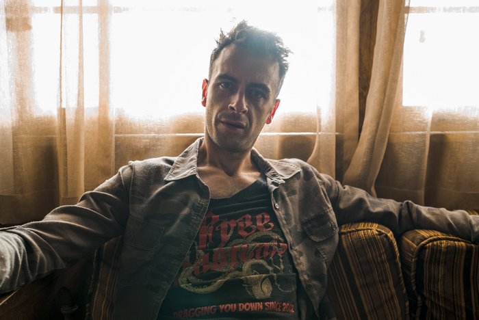 Joseph Gilgun sitting on a couch