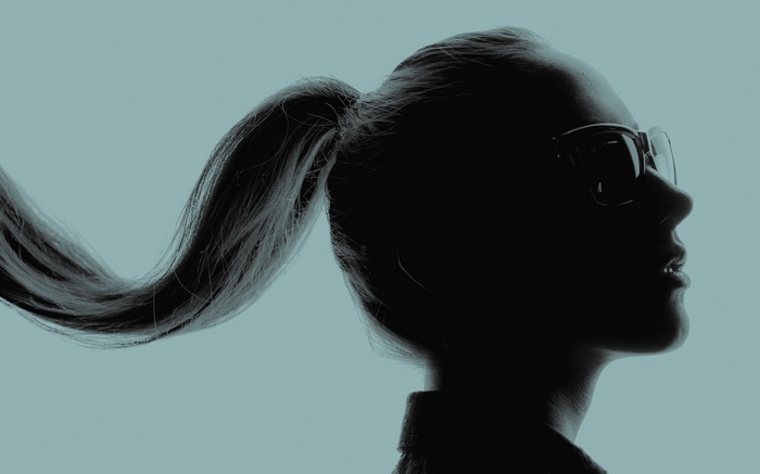 Silhouette of a woman with glasses and ponytail