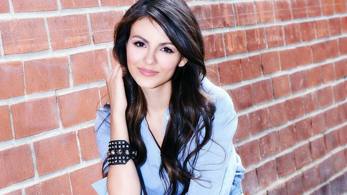 Victoria Justice posing against a brick wall