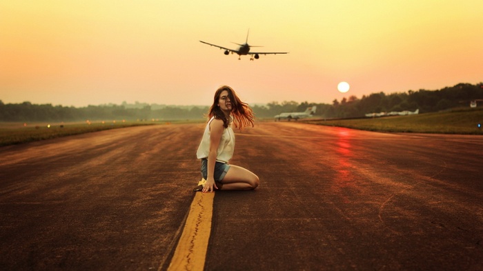 Woman on runway with airplane landing