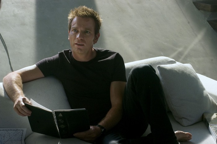 Ewan McGregor reading a book on a couch