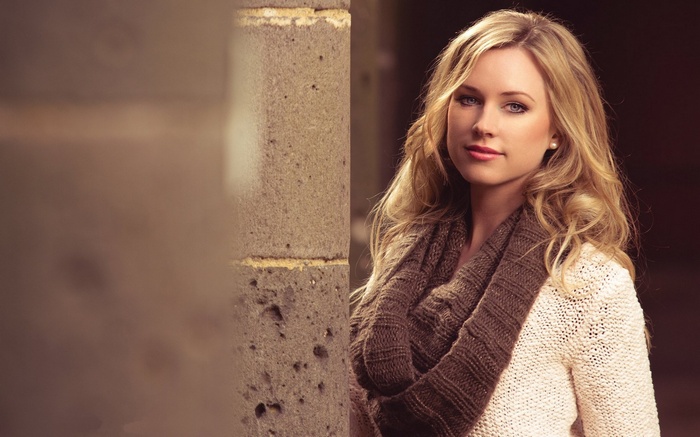 Woman with blonde hair wearing a scarf and sweater