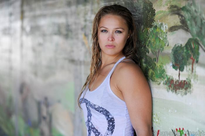 Ronda Rousey leaning against a painted wall