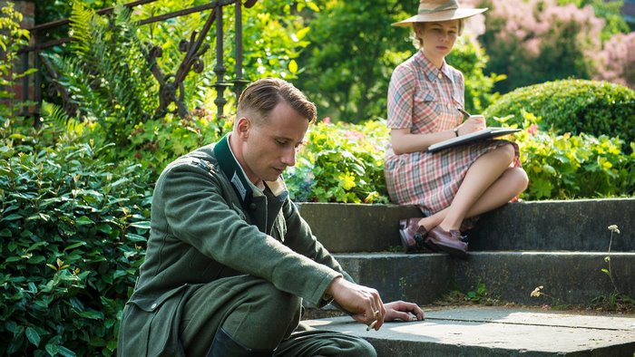 Man in uniform and woman with hat in garden