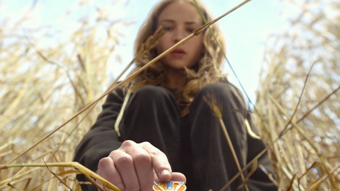 Britt Robertson in a field of tall grass