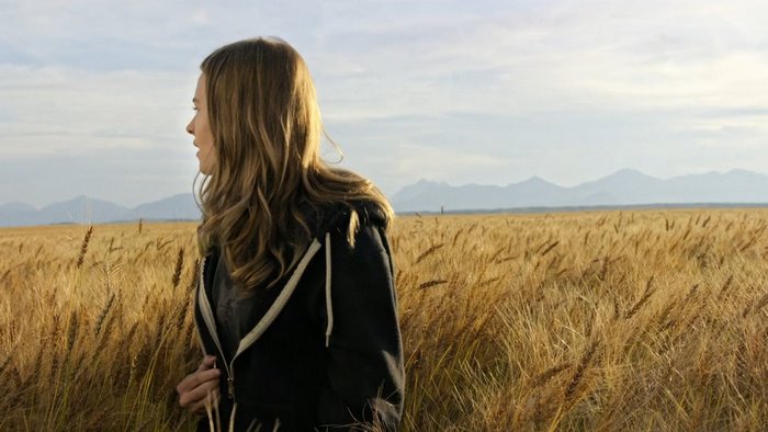Britt Robertson in a wheat field with mountains