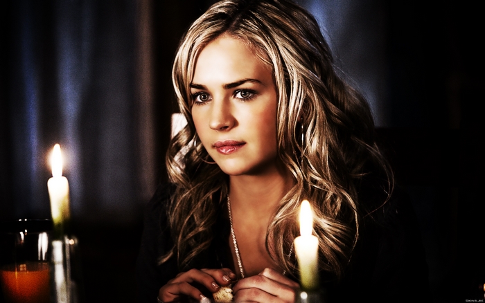 Britt Robertson sitting at a table with candles