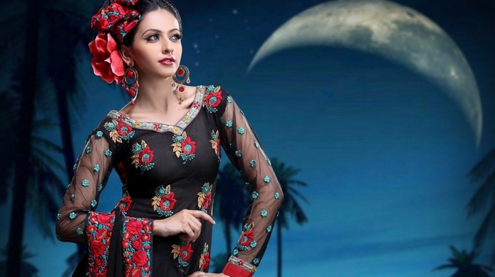 Woman in embroidered black dress with red flower in hair