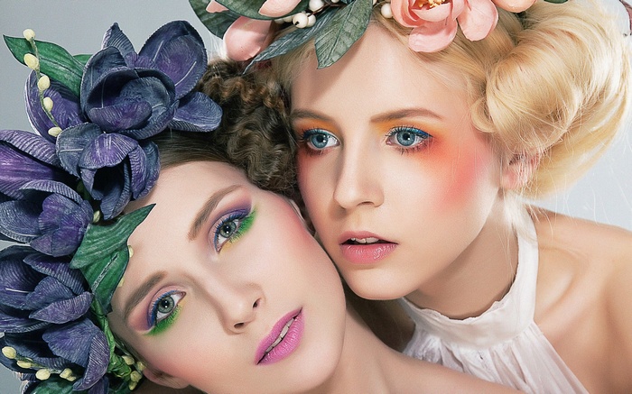 Two women with elaborate floral headdresses and makeup