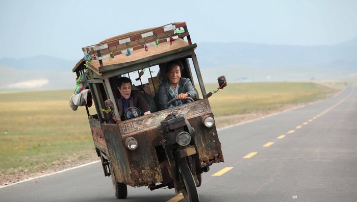 Jackie Chan in a rickety vehicle on a road