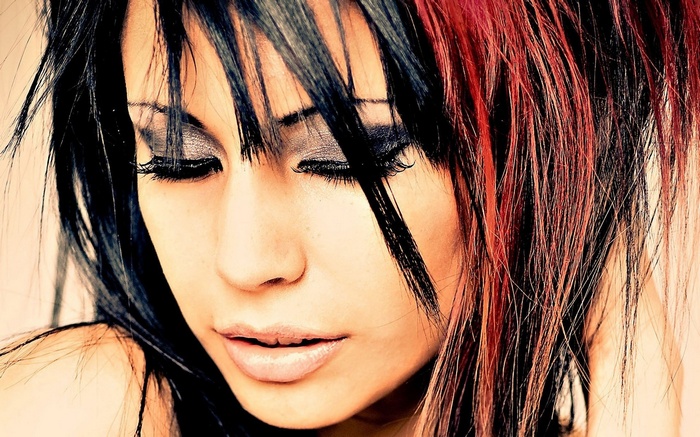 Woman with black and red streaked hair and heavy eye makeup