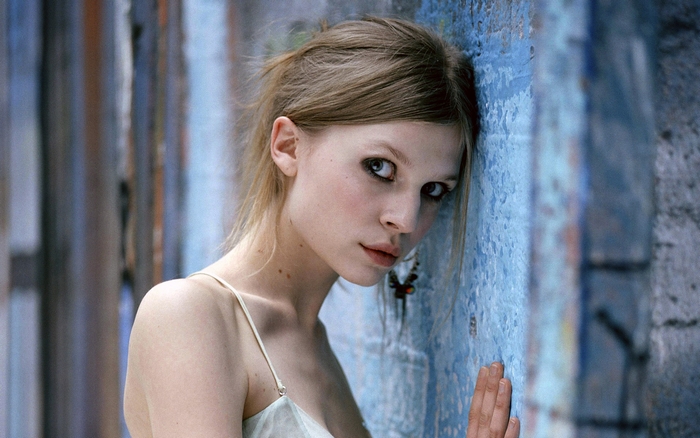 Clémence Poésy leaning against a blue wall