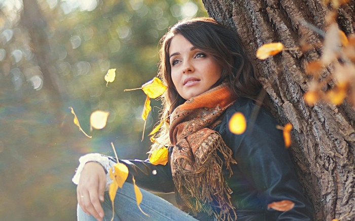Woman sitting by a tree in autumn