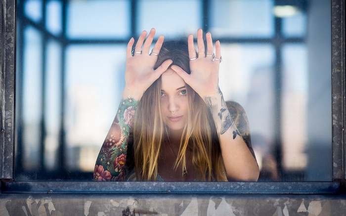 Woman with tattoos looking through a window