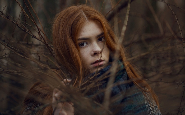 Young woman with red hair in branches