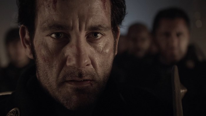 Clive Owen in a dark, possibly historical setting
