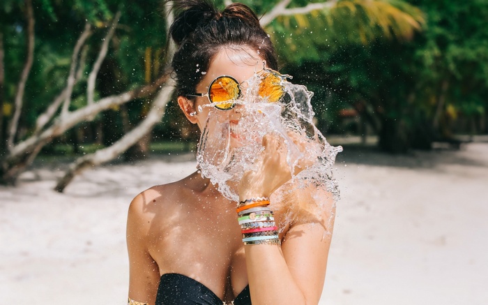 Woman splashing water on her face at the beach