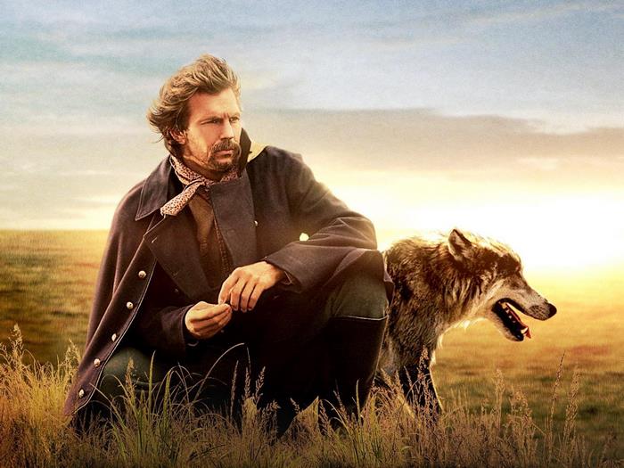 Kevin Costner with a wolf in a field