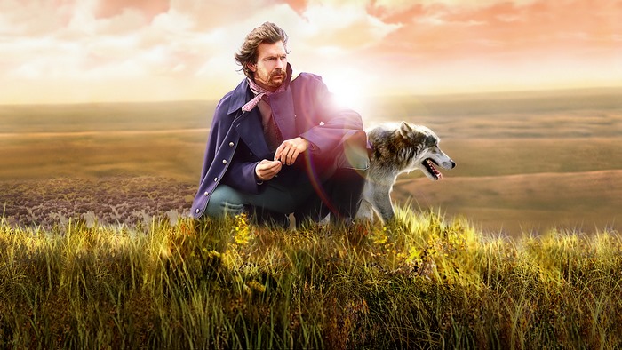 Kevin Costner with a wolf in a field